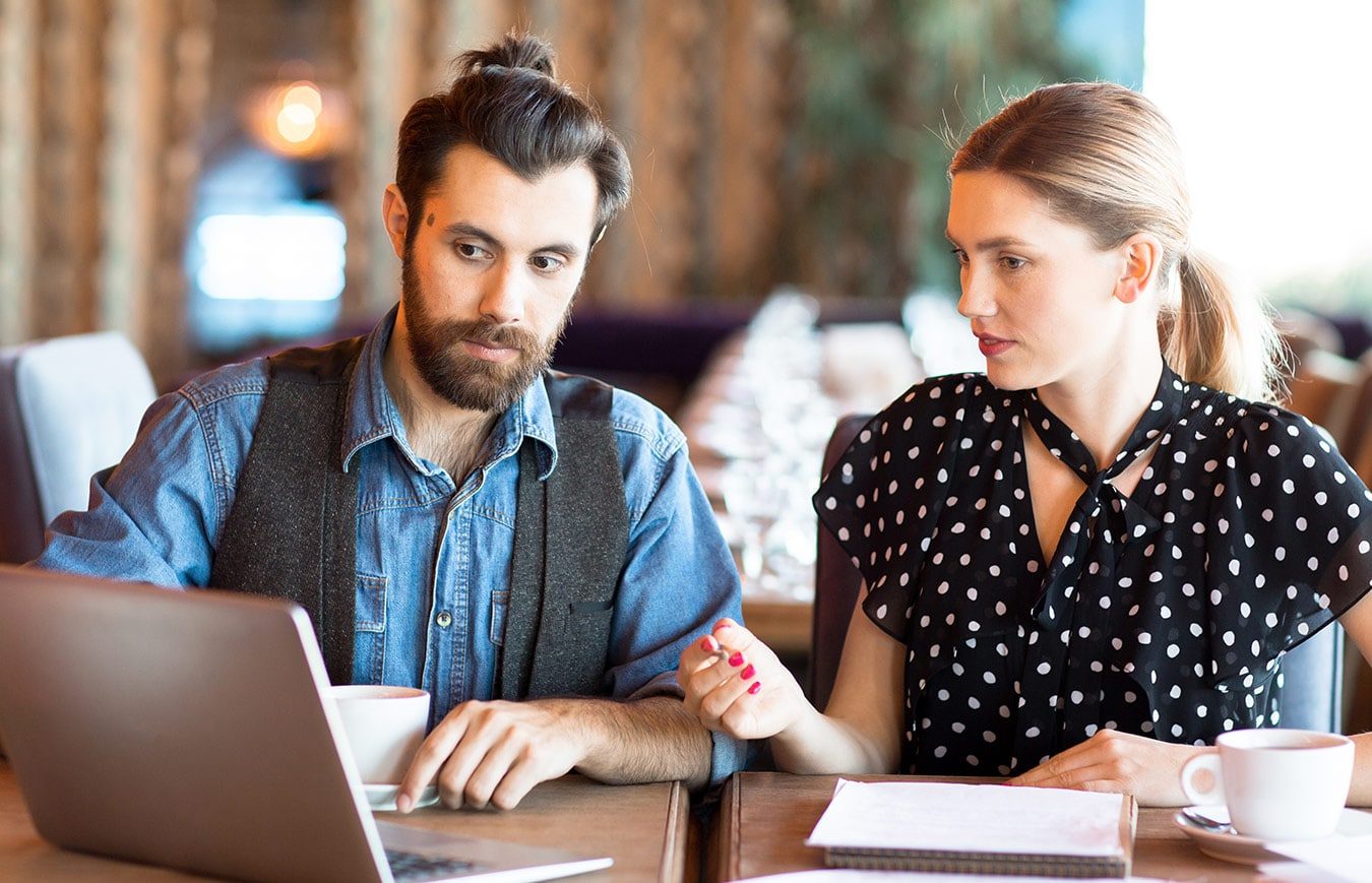 office workers having discussion in front of a laptop