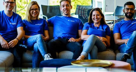eloomi employees sitting on the sofa and wearing eloomi t-shirts
