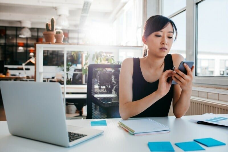 Woman sitting at her desk looking at her phone