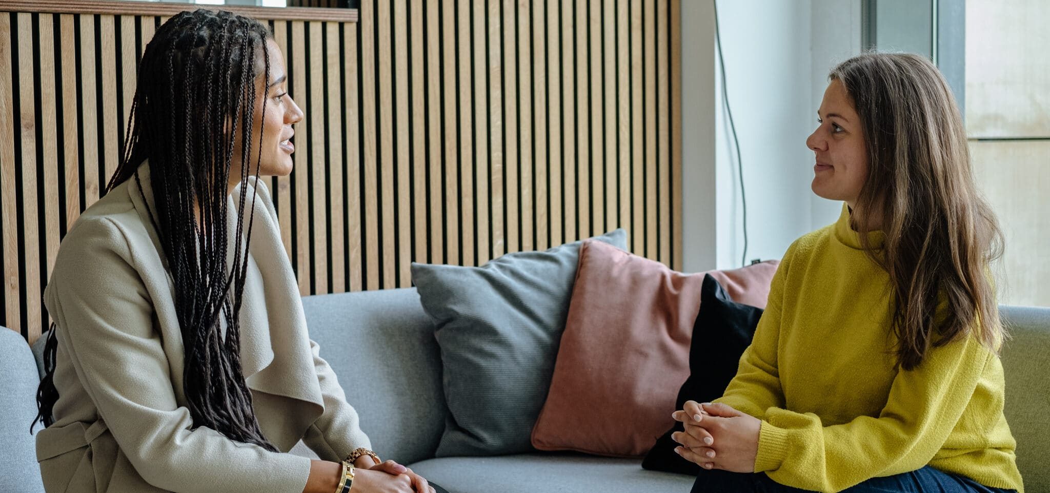 two women sitting on a couch and having a conversation