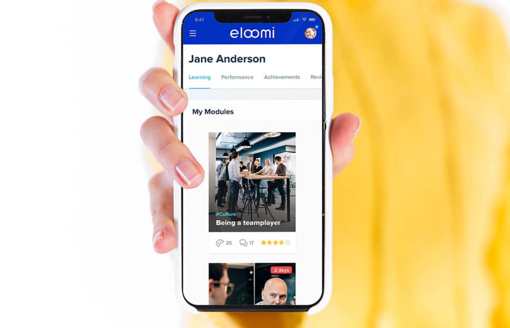 woman holding a mobile phone with eloomi platform lms module