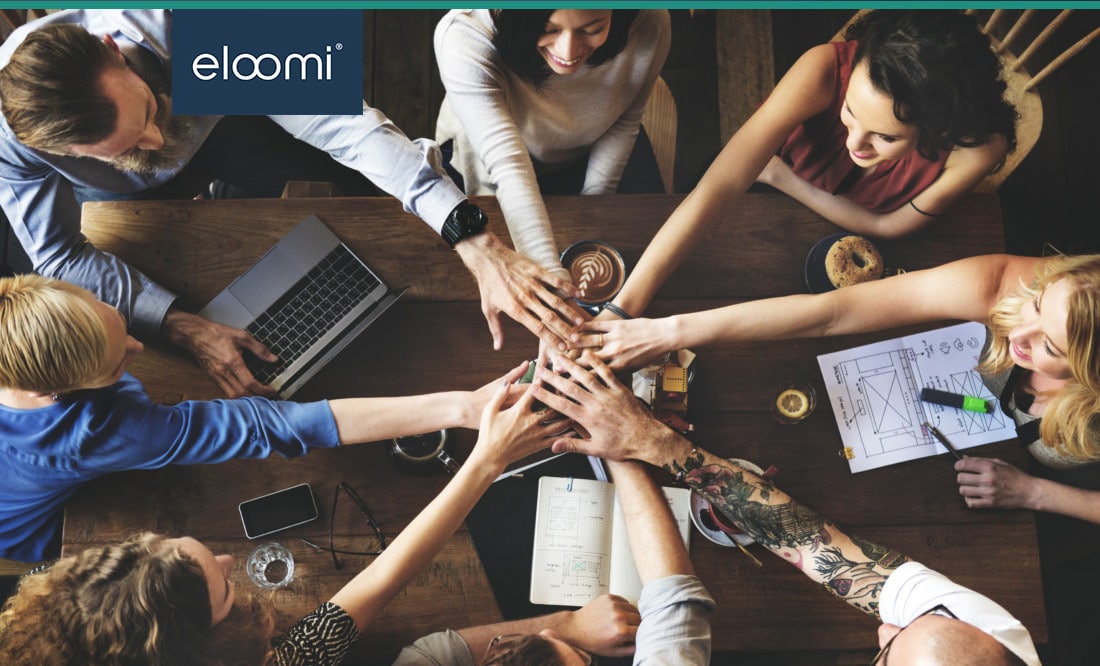A group of coworkers with their hands all in around a table