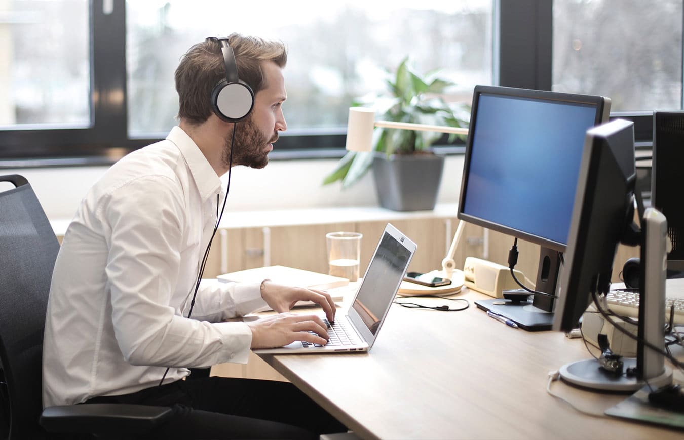 Man working at the computer and wearing headphones, taking e-learning module