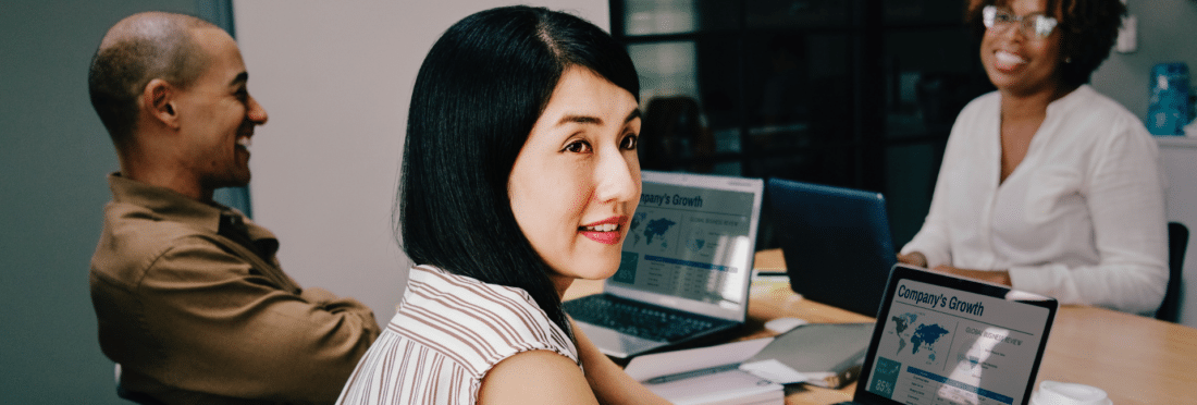 Asian woman sitting at a table with her coworkers in a meeting discussing the business