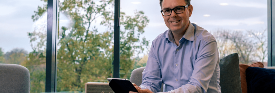 Man sitting with iPad on a couch smiling