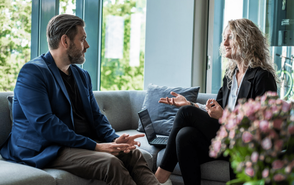 A man and woman sitting on a couch having a conversation on performance appraisal goals