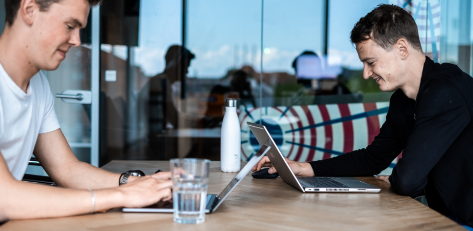 Two men sitting at table working on laptops Two men sitting at table working on laptops